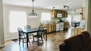 Uma cozinha ampla com armários de madeira, uma mesa de jantar com cadeiras e uma janela grande que oferece luz natural.