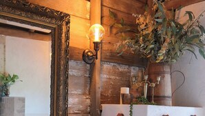 A rustic bathroom with a wooden vanity, a large mirror with an ornate frame, a vessel sink, and two wicker baskets.