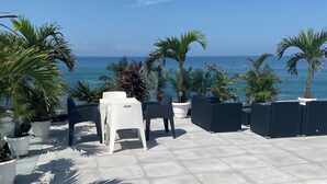A terrace with a view of the sea, featuring potted plants and outdoor furniture. - Modern Beachfront Luxury in Monrovia  (Monrovia)