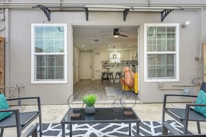 Een modern huis met een patio, voorzien van een glazen tafel, twee stoelen en een decoratieve plant.