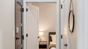 A hallway leading to a bedroom with a bed, bedside table, and lamp. - 2Bedroom, Near Over theRhine & Fountain Sq. + wifi (Cincinnati)