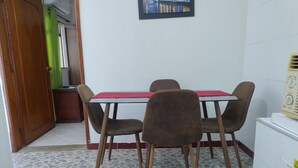 A dining area with a table and four chairs, a painting on the wall, and a washing machine in the corner. - Brown 101 rest house (Villavicencio)