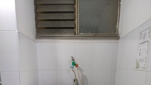A small bathroom with a white pedestal sink, a black trash bin, and a window with blinds. - Brown 101 rest house (Villavicencio)