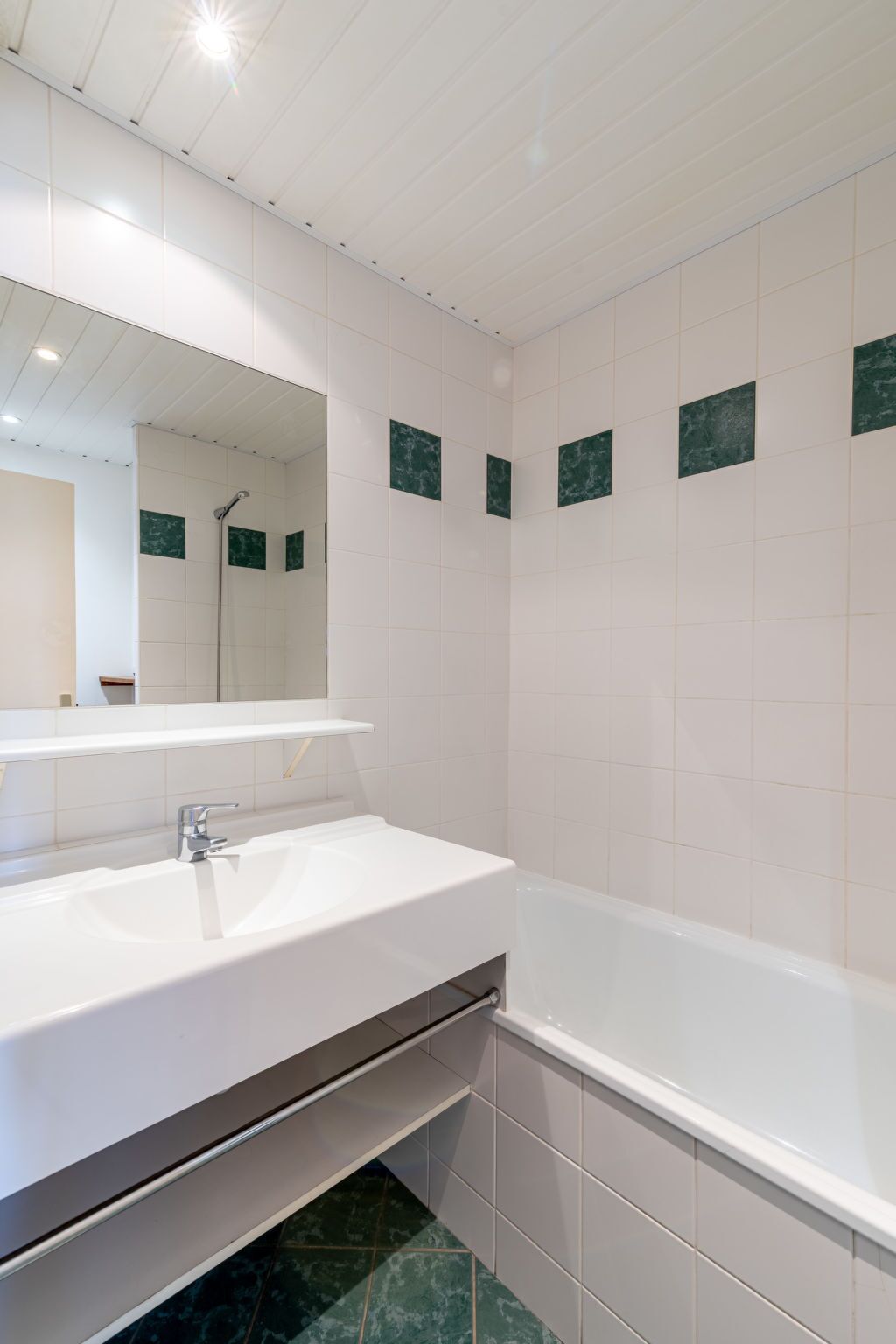 Ein modernes Badezimmer mit einem weißen Waschbecken, einem Spiegel und einer Badewanne.