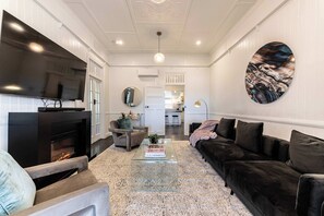 Una sala de estar moderna con chimenea, un televisor de pantalla plana grande, un sofá de cuero negro y una mesa de centro.