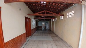 A corridor with tiled flooring, wooden beams on the ceiling, and a door on the left. - Hotel Toronto pgm (Paragominas)