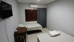 A small, clean room with two beds, a desk, a chair, a TV, and an air conditioning unit. - Hotel Toronto pgm (Paragominas)