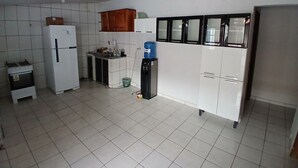 A compact kitchen with white cabinets, a refrigerator, a sink, and a water dispenser. - Hotel Toronto pgm (Paragominas)