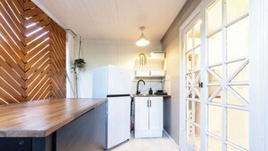 A compact kitchen with a wooden herringbone wall, a white refrigerator, a sink, and a hanging plant. - Urban Getaway Apartment Ipswich perfect for work (Newtown)