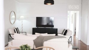Een woonkamer met een bank, een televisie en een lamp.