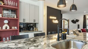 Cocina moderna con encimera de mármol, pileta de acero inoxidable e iluminación colgante.
