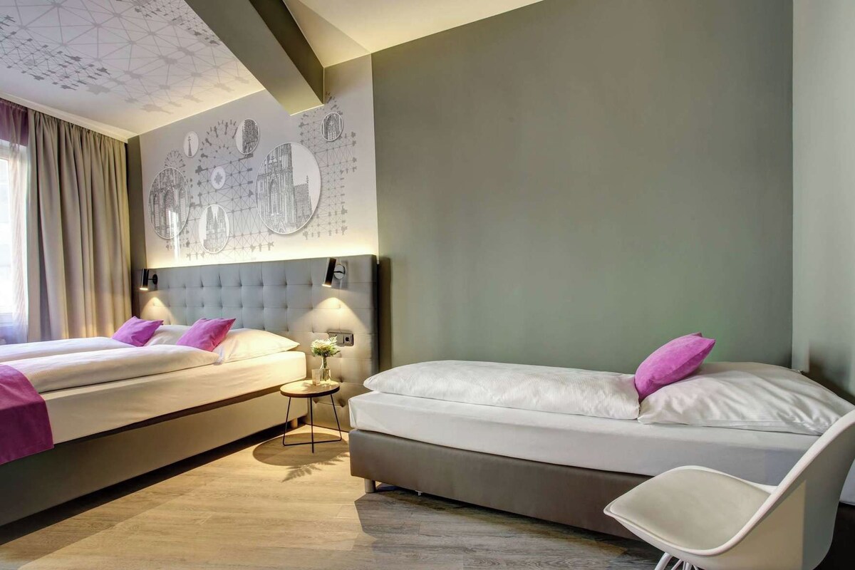 A hotel room with two beds, a round table, and a chair.