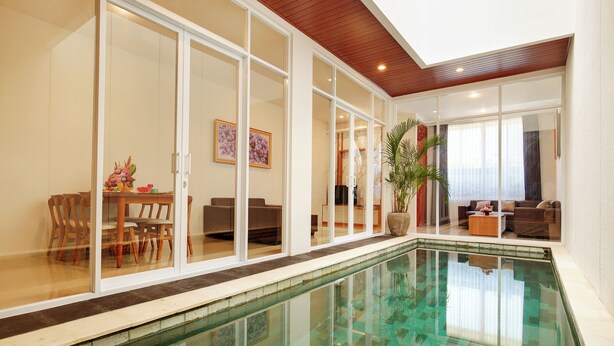 A modern indoor pool with glass walls, a wooden ceiling, and a dining area with chairs and a table. - Brand New Villa Tentrem 2 Canggu  (Canggu)