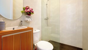 A bathroom with a wooden vanity, a white sink, a toilet, and a glass-enclosed shower. - Brand New Villa Tentrem 2 Canggu  (Canggu)