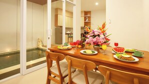 A dining area with a wooden table, chairs, and a view of a swimming pool through glass doors. - Brand New Villa Tentrem 2 Canggu  (Canggu)