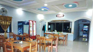 Un restaurante con mesas y sillas de madera, un refrigerador y una barra con el menú.