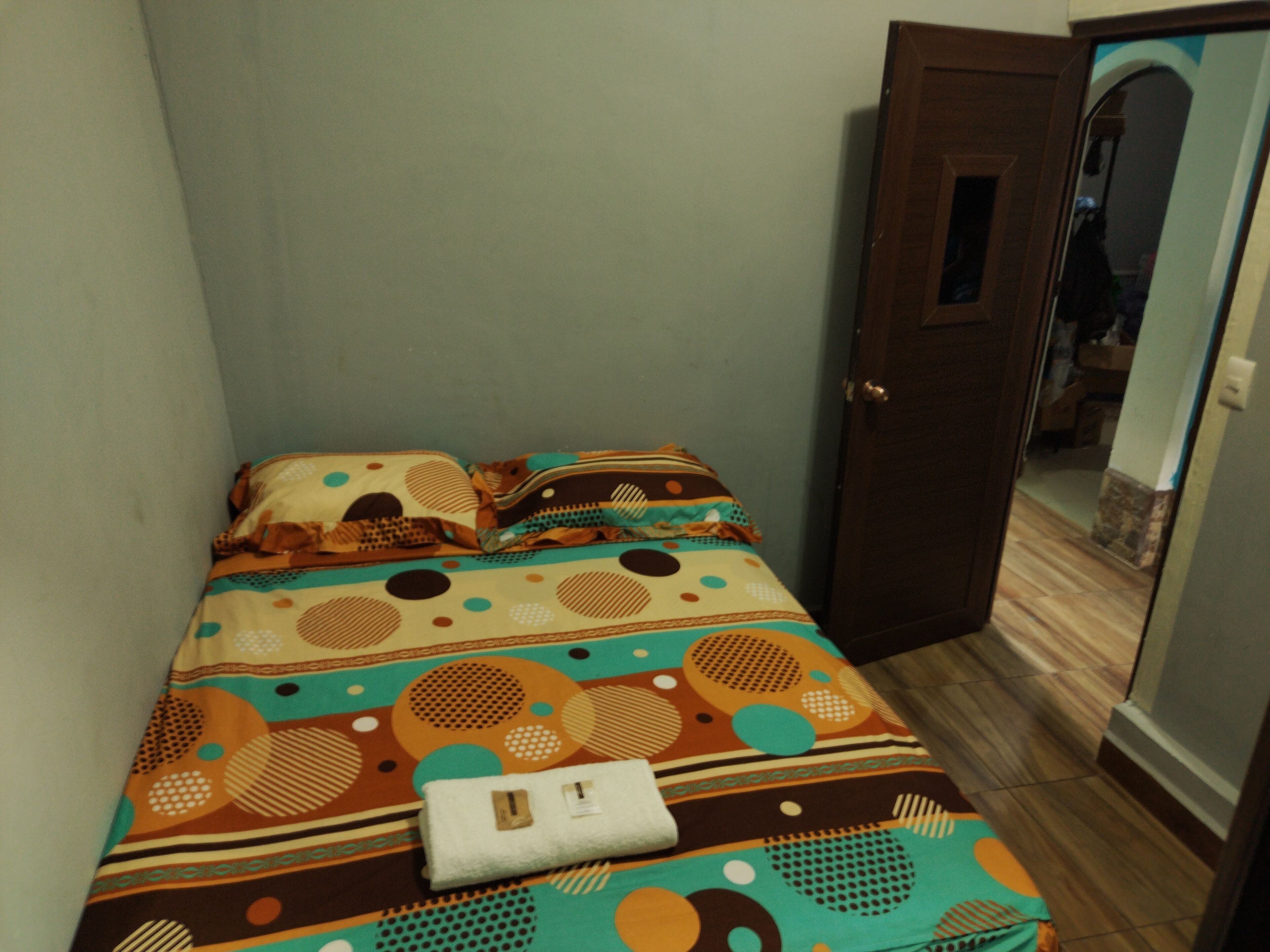 Una habitación pequeña con cama, puerta y espejo.