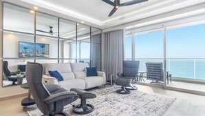 A modern living room with a sofa, two armchairs, a coffee table, and a view of the ocean through large windows. - Amaizing condo by the beach Encantame W1704 (Puerto Peñasco)