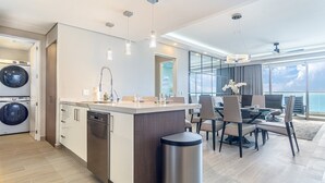 A modern kitchen with built-in appliances, a dining area with a view, and a large window. - Amaizing condo by the beach Encantame W1704 (Puerto Peñasco)