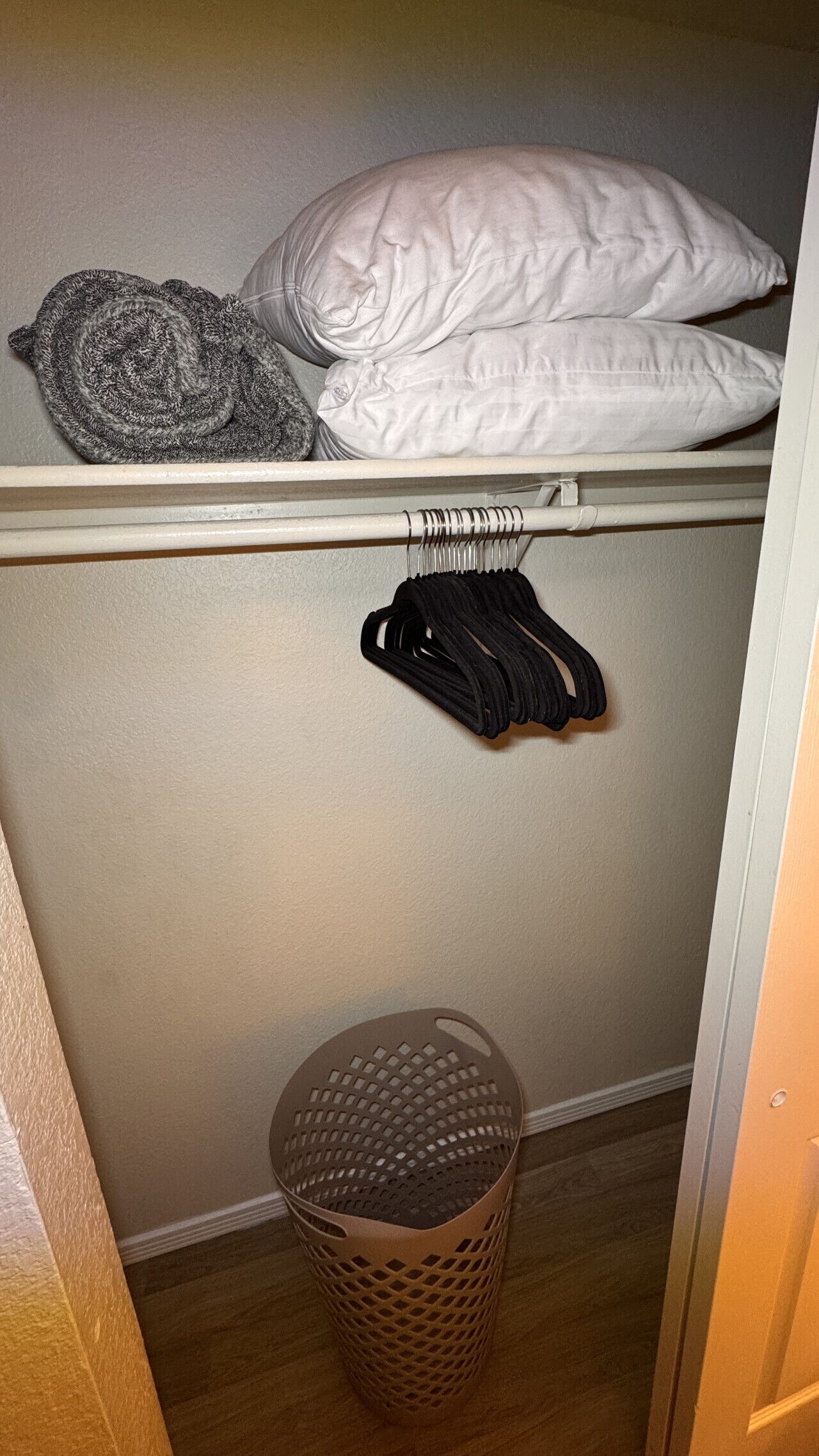 Ein Schrank mit Kleiderstange, einem Korb und gefalteten Decken.