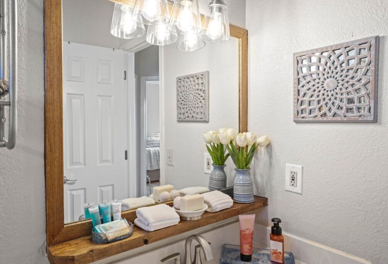 A bathroom with a wooden vanity, a large mirror, and toiletries.