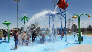 Een waterpark met verschillende speelconstructies en een helderblauwe lucht.