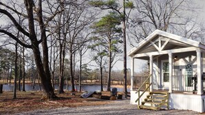 A cabin with a porch and steps, surrounded by trees and a body of water. - Farm Stay with Highland Cows (Mulberry)