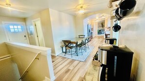 Une cuisine moderne équipée d’une machine à café, un coin repas avec une table et des chaises, et un escalier menant à un autre niveau.