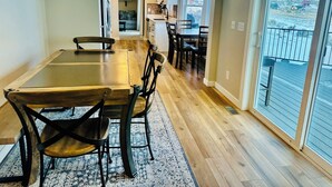 Un coin repas avec une table et des chaises en bois, un tapis et une vue sur un paysage enneigé par de grandes fenêtres.