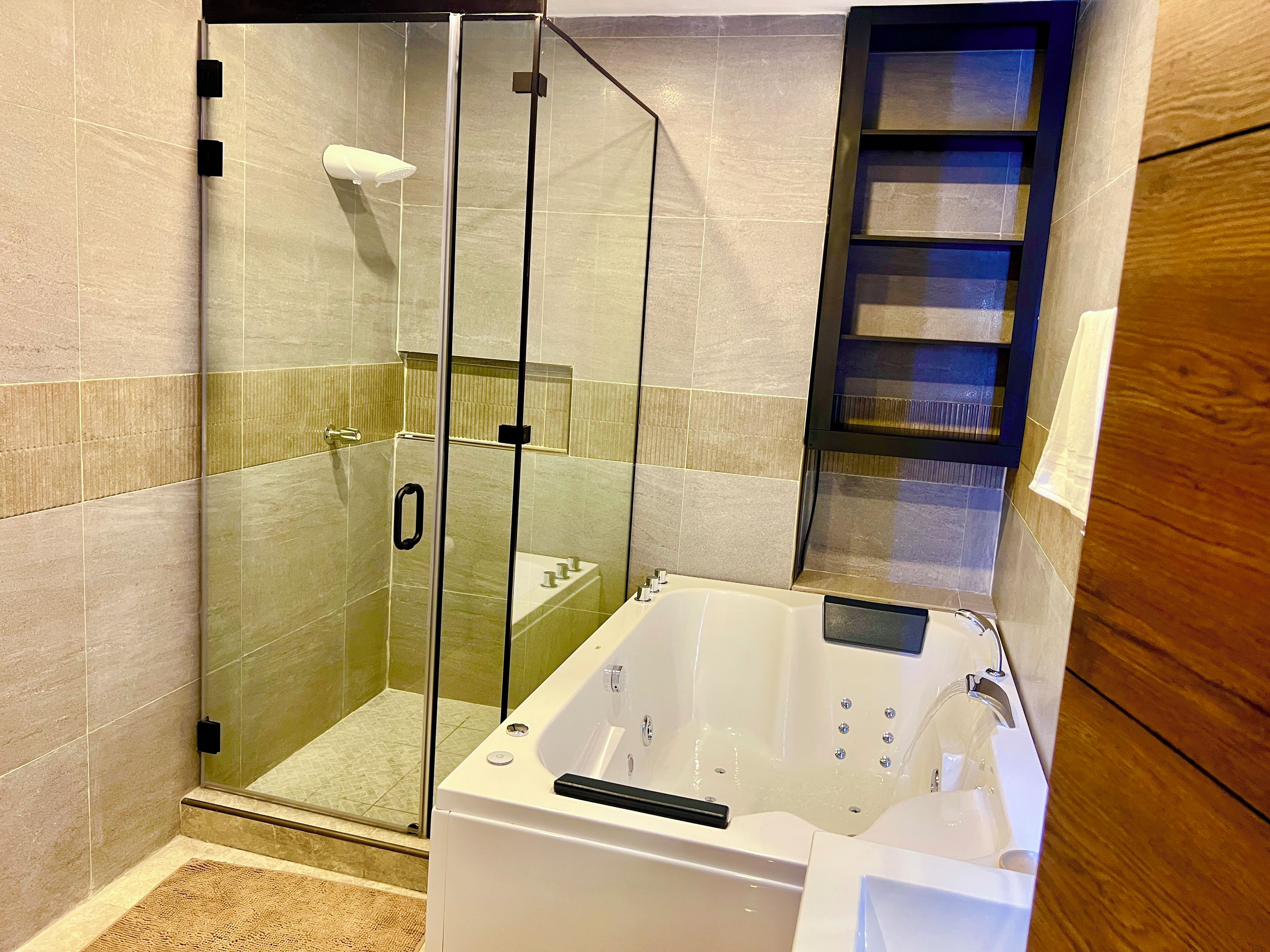Un baño moderno con ducha envuelta en vidrio, bañera blanca y tocador de madera.