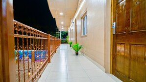 A corridor with a tiled floor, wooden doors, and a railing with string lights. - Hotel Five Stars sv (Berlin)