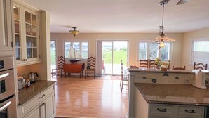 Una cocina amplia con armarios de madera, un comedor con un modelo de velero y vistas a través de puertas de cristal.