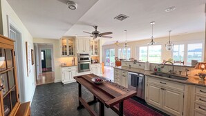 Una cocina amplia con armarios blancos, una mesa de comedor de madera y una alfombra roja.