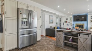 A modern kitchen with stainless steel appliances, a built-in oven, and a farmhouse-style bar area with a TV.