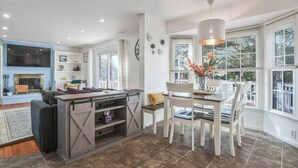 A modern kitchen with a dining area, large windows, and a fireplace.