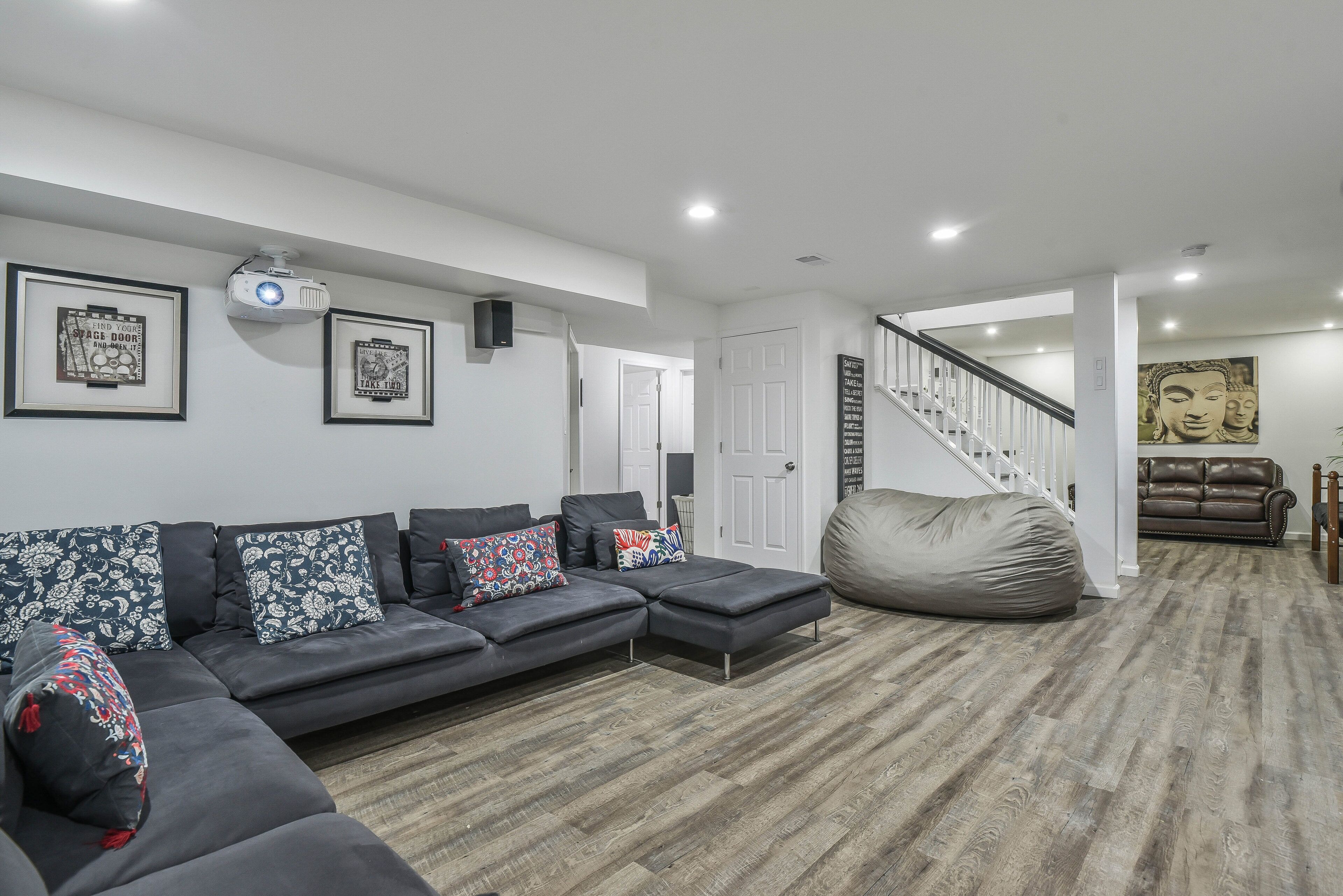 A modern living room with a sectional sofa, a bean bag, and a staircase leading to another level.