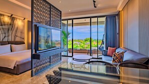 A modern living room with a large TV, comfortable seating, a glass coffee table, and a view of the outdoors. - The One Umalas (Kerobokan)