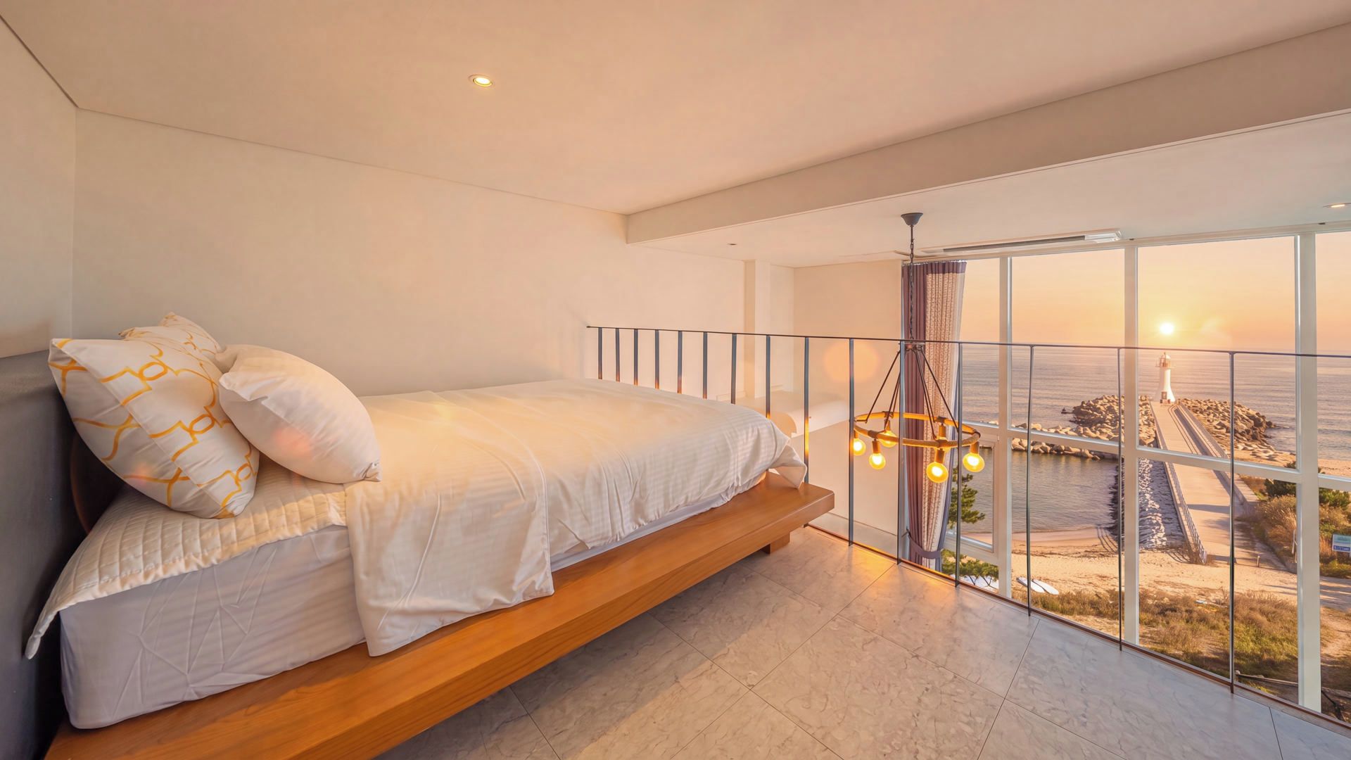A bedroom with a bed, a view of the sea, and a balcony.
