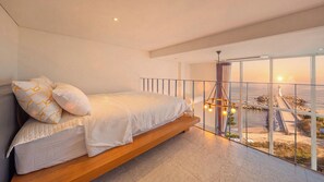 A bedroom with a bed, a view of the sea, and a balcony. - Gangneung Meerbrick Spa Pension (Gangneung)