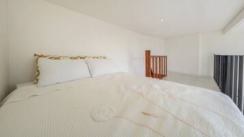 Un dormitorio moderno con una cama grande, un cabecero de madera y una escalera que lleva a un nivel superior.