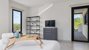 A modern bedroom with a bed, a wooden tray with breakfast items, a TV, and a grey cabinet. - Modern NEW 2BR1BA ~ Nature Escape ~ Great Location (Paradera)