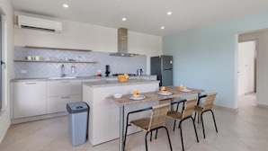 A modern kitchen with white cabinetry, a central island with seating, and a built-in oven. - Modern NEW 2BR1BA ~ Nature Escape ~ Great Location (Paradera)