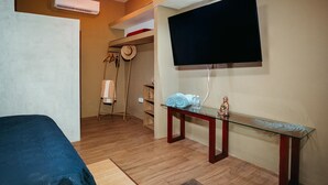 Une chambre d’hôtel avec un lit, une table en verre avec des serviettes, une télévision et un porte-chapeaux.