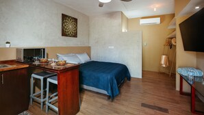 Une petite chambre comprenant un lit, un coin cuisine et un ventilateur de plafond.