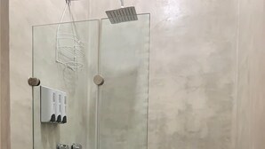 Une salle de bain avec une douche à parois de verre, des toilettes et un petit lavabo.