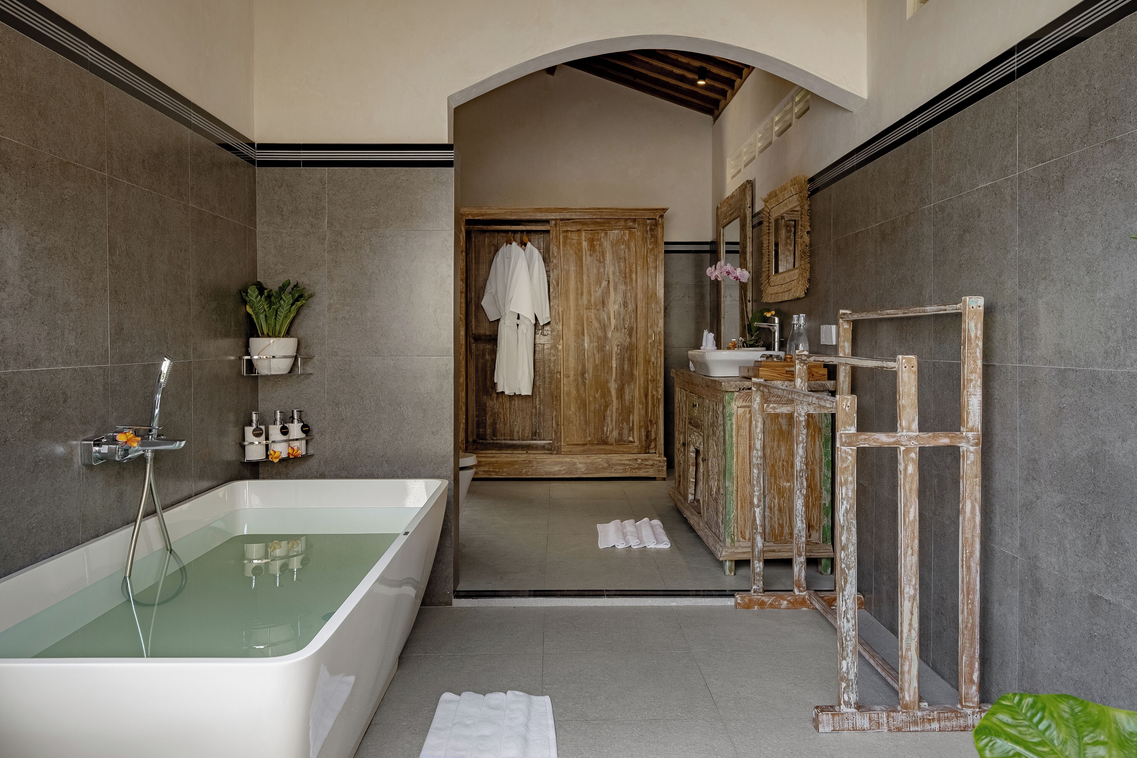 A modern bathroom with a freestanding bathtub, a wooden vanity, and a mirror above the sink.