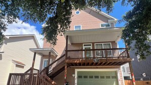 A two-story house with a balcony, a garage, and a front yard. - Ocean View Beach House. Sleeps 8 Coastal Luxe. Seabreeze! (Norfolk)