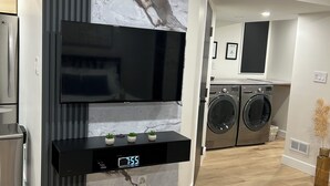 Een moderne keuken met een ingebouwde televisie, een digitale klok en een marmeren spatwand.