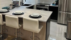 Een moderne keuken met een centraal eiland, roestvrijstalen apparatuur en houten keukenkastjes.