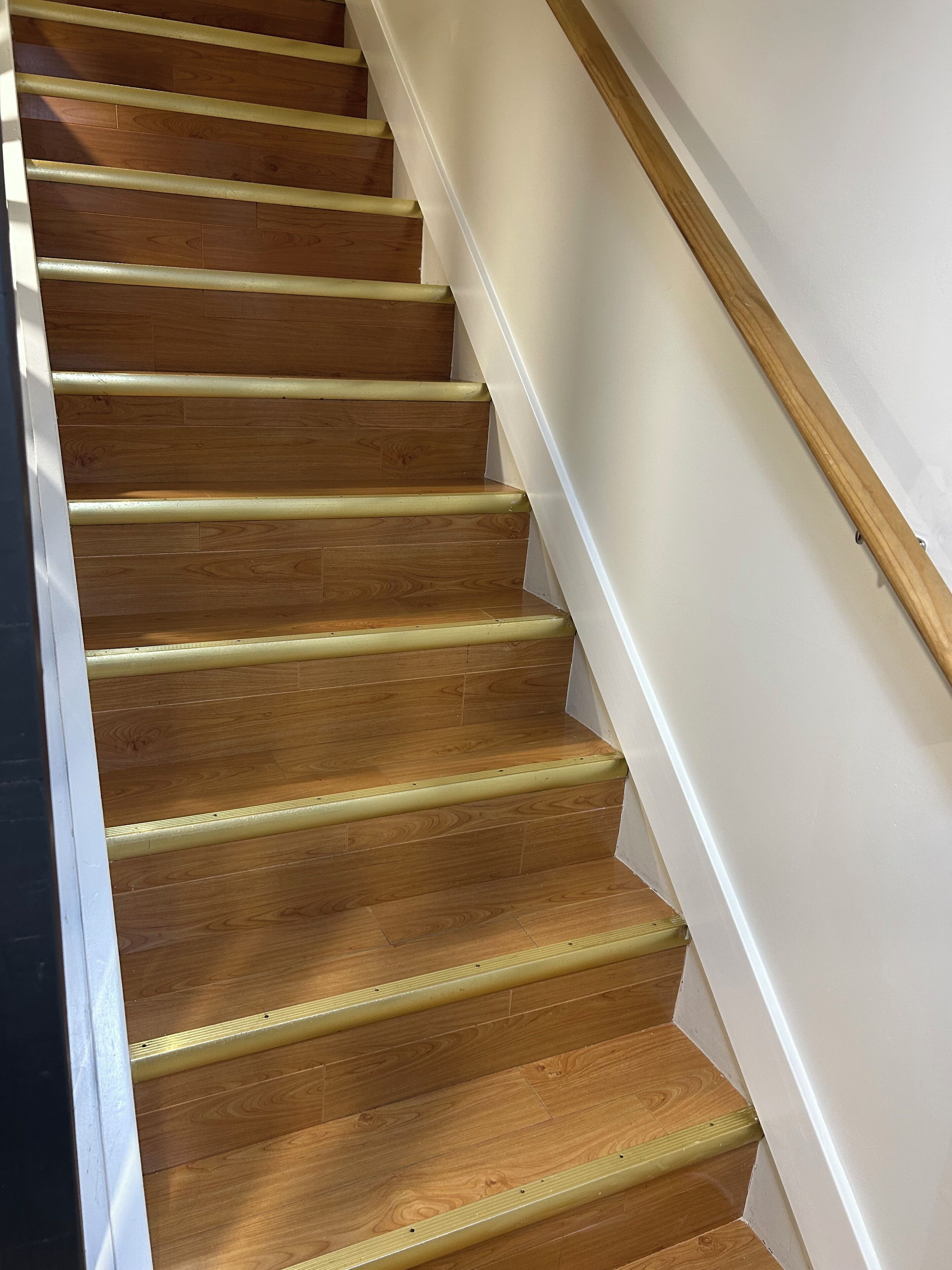 Un escalier en bois, avec des murs blancs et une rampe en bois.